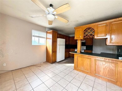 Kitchen with kitchen peninsula, white appliances, ceiling fan, light tile patterned floors, and a textured ceiling