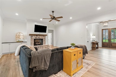 Living area with ceiling fan, light wood-style flo