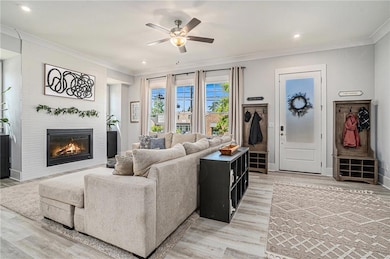 Living room with ornamental molding, ceiling fan, light wood finished floors, a fireplace, and recessed lighting