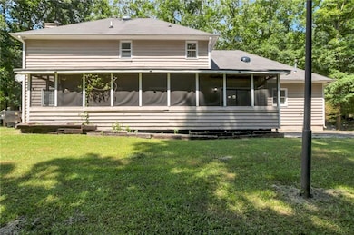 Back of property with a sunroom, a chimney, a lawn, and a shingled roof