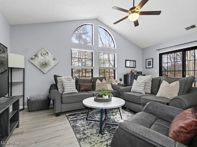 Living room featuring ceiling fan, high vaulted ceiling, and light wood-style flooring