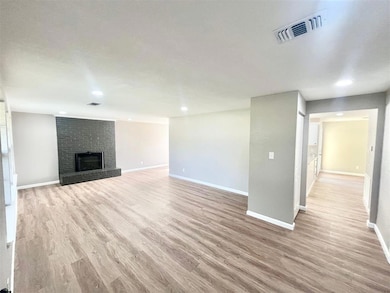 Unfurnished living room with light wood-style flooring, a brick fireplace, and recessed lighting