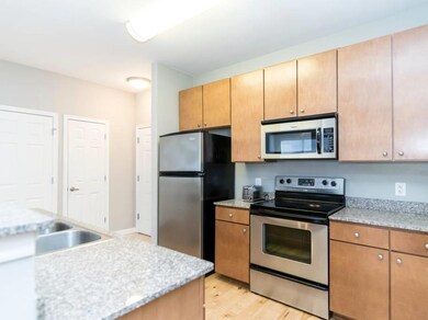 Kitchen featuring stainless steel appliances, light wood-style flooring, light stone countertops, and brown cabinets
