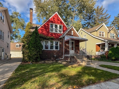 View of front of house featuring brick siding, a front yard, a chimney, a garage, and covered porch