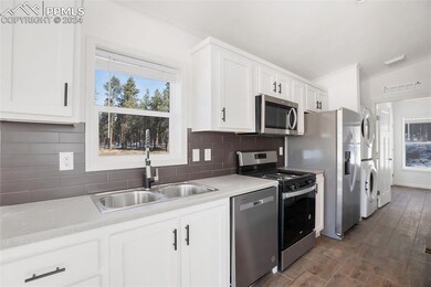 Kitchen with white cabinetry, sink, stacked washer