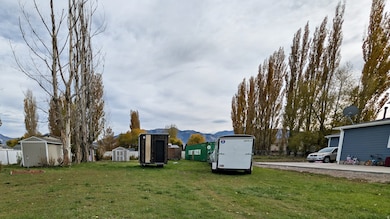 View of grassy yard featuring a storage unit and a mountain view