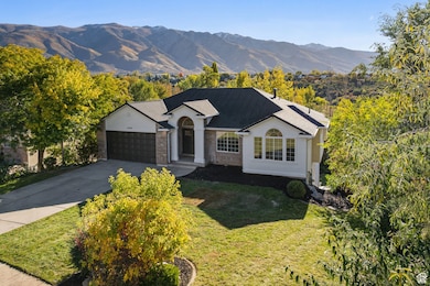 Ranch-style home with a mountain view, driveway, a garage, a front yard, and stucco siding