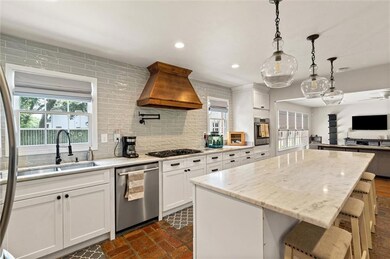 Kitchen with stainless steel appliances, premium range hood, decorative backsplash, recessed lighting, and a center island