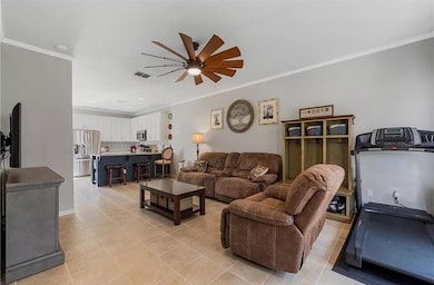 Living room with ornamental molding, ceiling fan, and light tile patterned floors