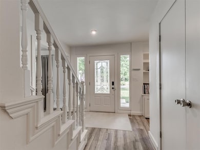 Foyer entrance featuring light wood-type flooring, plenty of natural light, stairway, and baseboards