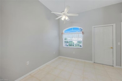 Unfurnished room featuring baseboards, a ceiling fan, light tile patterned floors, and lofted ceiling