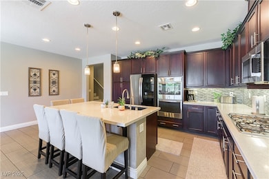 Kitchen with appliances with stainless steel finishes, tasteful backsplash, a breakfast bar, light countertops, and recessed lighting