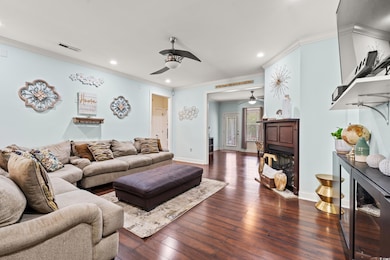 Living room with a ceiling fan, recessed lighting, ornamental molding, dark wood-type flooring, and baseboards