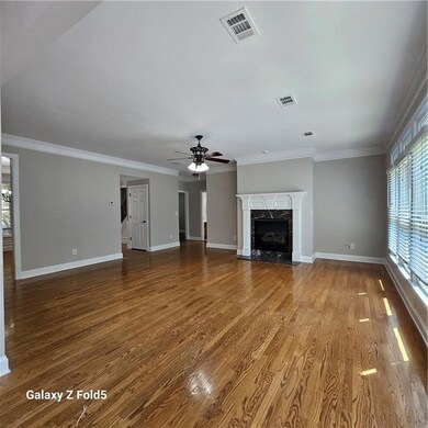 Unfurnished living room featuring ceiling fan, a high end fireplace, wood finished floors, and crown molding