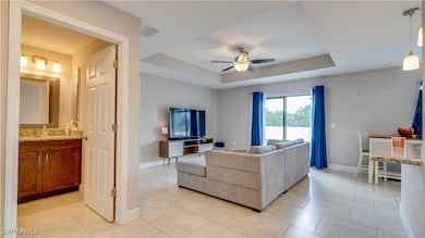 Living area with ceiling fan, a raised ceiling, ba