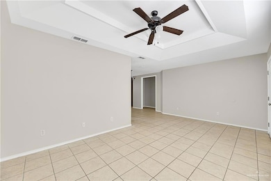 Unfurnished room with a raised ceiling, a ceiling fan, baseboards, and light tile patterned floors