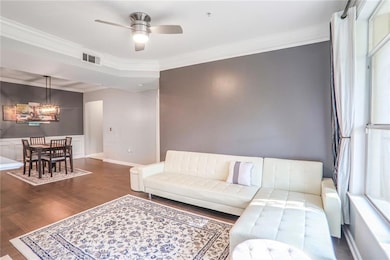 Living room with a chandelier, wood finished floors, ornamental molding, a ceiling fan, and baseboards