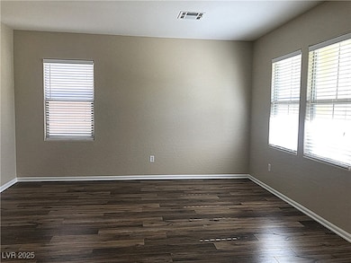 Empty room featuring baseboards and dark wood finished floors