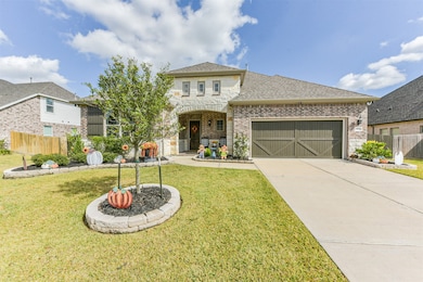This inviting front yard showcases lush landscaping, stone-bordered flower beds, and a charming covered porch. The double garage with wood-style doors adds a touch of elegance.