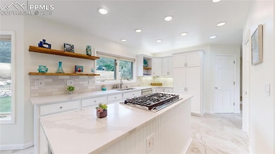 Kitchen featuring open shelves, a sink, decorative backsplash, a center island, and white cabinets