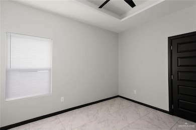 Spare room featuring light marble finish flooring and a ceiling fan