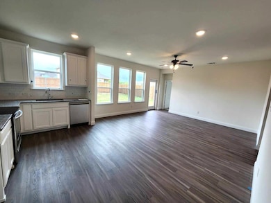 Kitchen featuring ceiling fan, dark hardwood / wood-style flooring, appliances with stainless steel finishes, backsplash, and white cabinetry