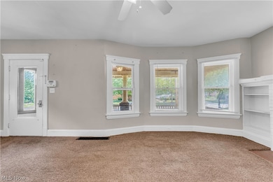 Carpeted spare room featuring ceiling fan