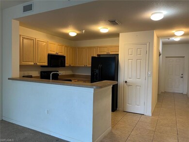 Kitchen with light brown cabinetry, sink, black ap