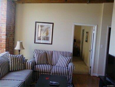 Spacious living room with oak floors, brick wall a