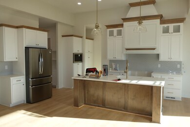 Kitchen featuring tasteful backsplash, appliances with stainless steel finishes, light wood finished floors, recessed lighting, and a kitchen island with sink