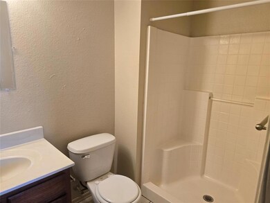 Full bath featuring a textured wall, toilet, a sho