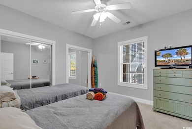 Carpeted bedroom with ceiling fan and a closet