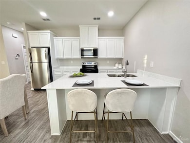 Kitchen featuring white cabinetry, a kitchen breakfast bar, a peninsula, appliances with stainless steel finishes, and recessed lighting