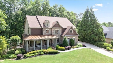 View of front of property featuring covered porch, a front yard, driveway, a standing seam roof, and a garage