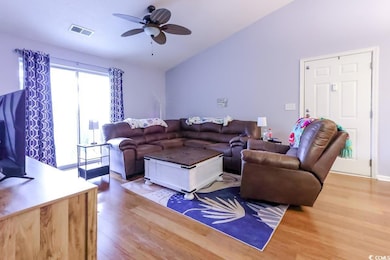 Living area featuring wood finished floors, vaulted ceiling, and a ceiling fan