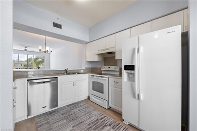 Kitchen featuring white & stainless steel appliances light wood-style floors, under cabinet range hood, and white cabinetry
