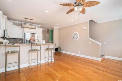 Kitchen with a breakfast bar area, crown molding, appliances with stainless steel finishes, white cabinetry, and recessed lighting