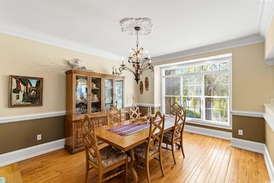 Dining area with a chandelier, baseboards, light wood-style floors, and ornamental molding