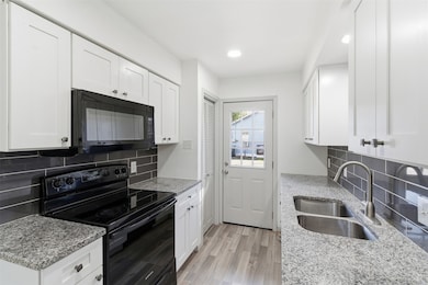 Kitchen featuring black appliances, tasteful backsplash, white cabinetry, and recessed lighting