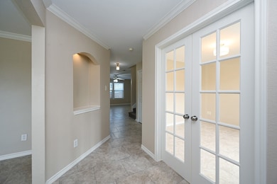 Hall featuring french doors, crown molding, and baseboards