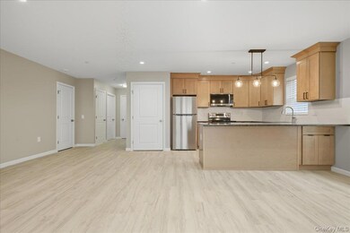 Kitchen Featuring Appliances with Stainless Steel Finishes, Hanging Light Fixtures, Peninsula & Granite Countertops,