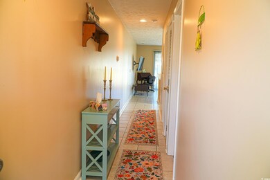 Hall with light tile patterned floors, recessed li