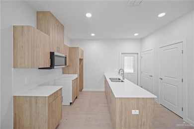 Kitchen with visible vents, modern cabinets, stainless steel microwave, a sink, and recessed lighting