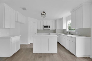 Kitchen featuring a kitchen island, white cabinets, sink, and light hardwood / wood-style floors