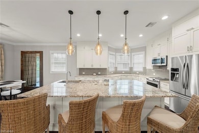 Kitchen featuring stainless steel appliances, tasteful backsplash, crown molding, and a kitchen island with modern lighting