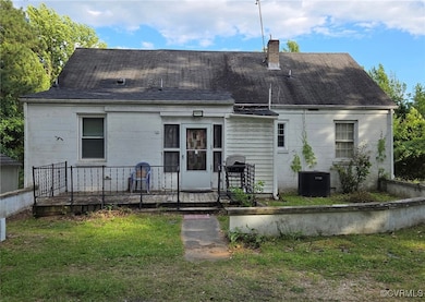 Rear view of property with a chimney, a lawn, a sh