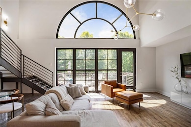 Living area featuring baseboards, wood finished floors, a towering ceiling, and stairs