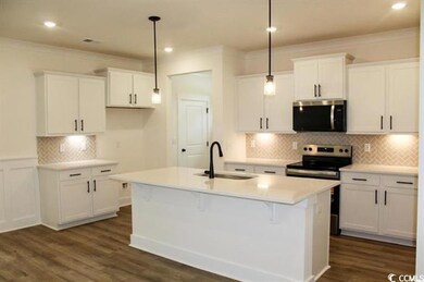 Kitchen featuring decorative backsplash, white cabinetry, crown molding, pendant lighting, and stainless steel appliances