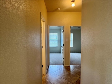 Hallway featuring a textured wall, tile patterned
