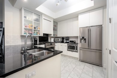 Kitchen featuring stainless steel appliances, light marble finish floors, white cabinetry, glass insert cabinets, and recessed lighting